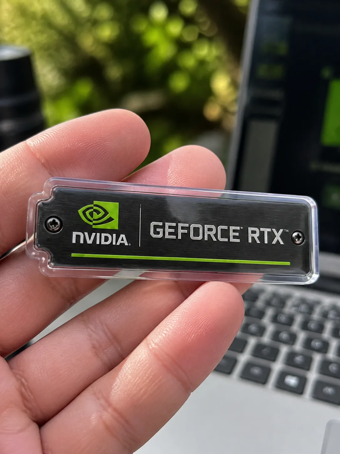 GeForce RTX acrylic keychain held beside a laptop
